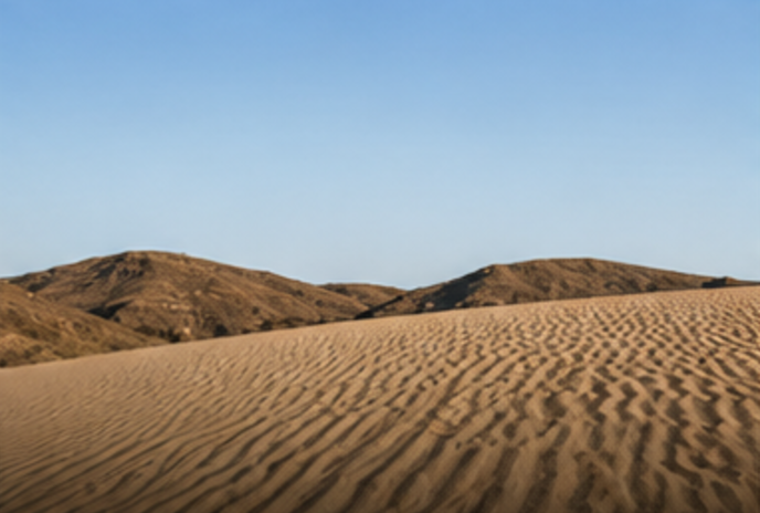 Rippled sand dune stretching toward dry hills