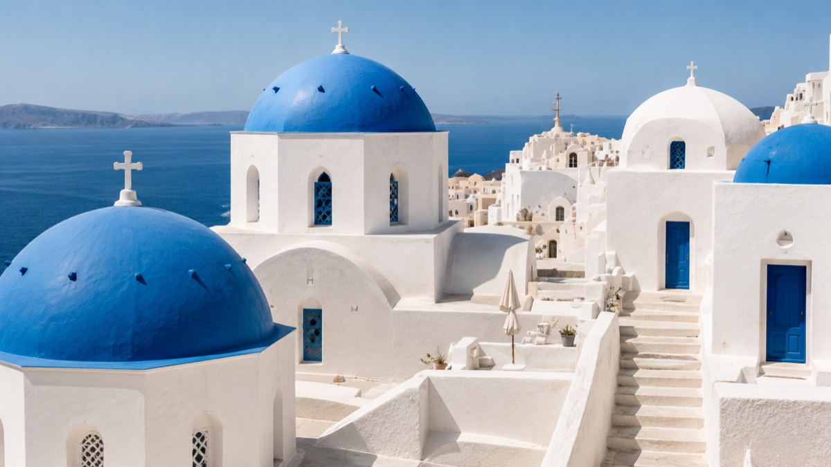 Whitewashed village lane with a blue-domed church overlooking the sea