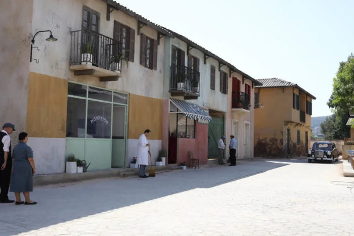 Built village street set with period storefronts and background actors